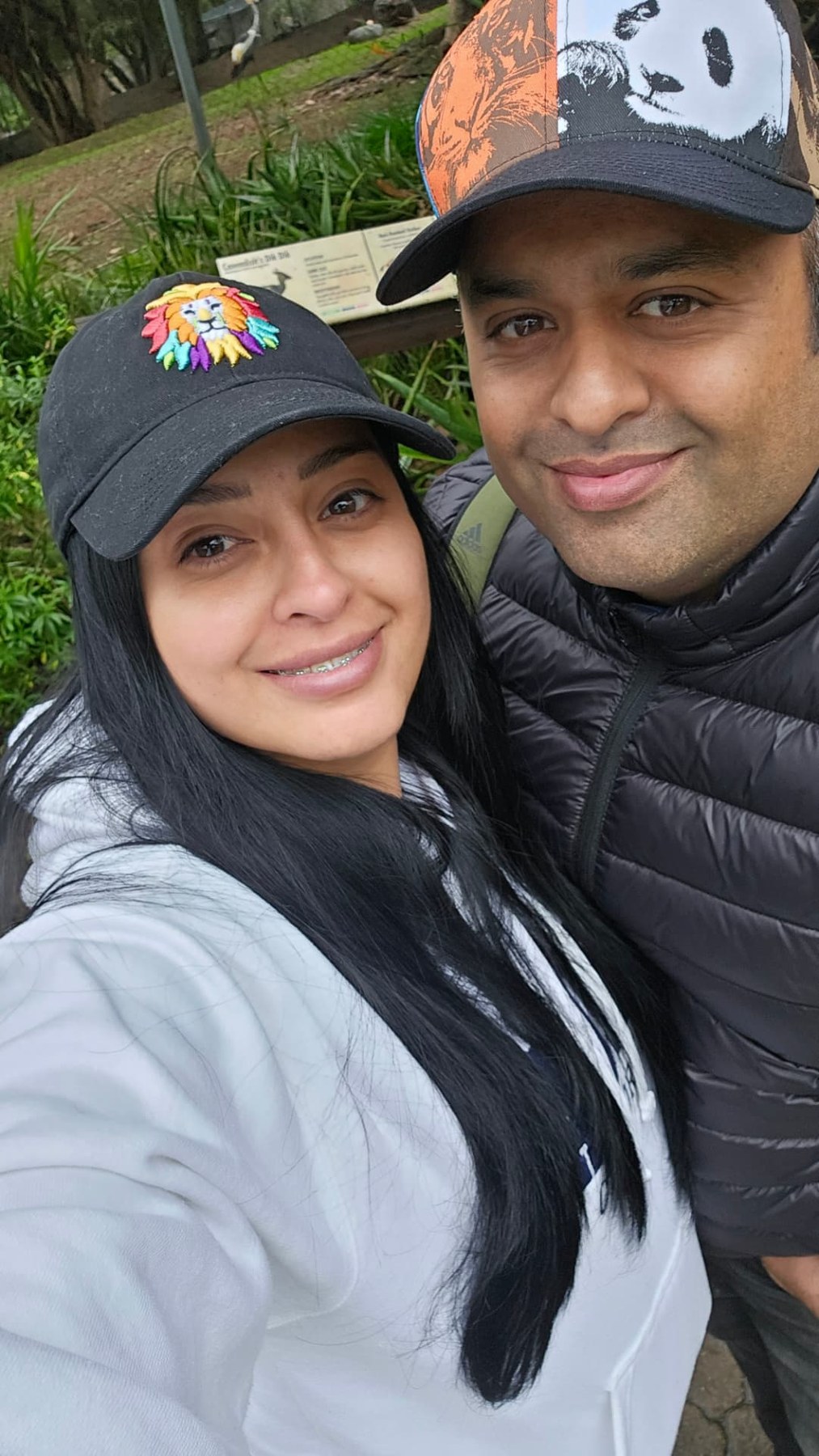 Margarita and Samir smiling in their caps at the zoo